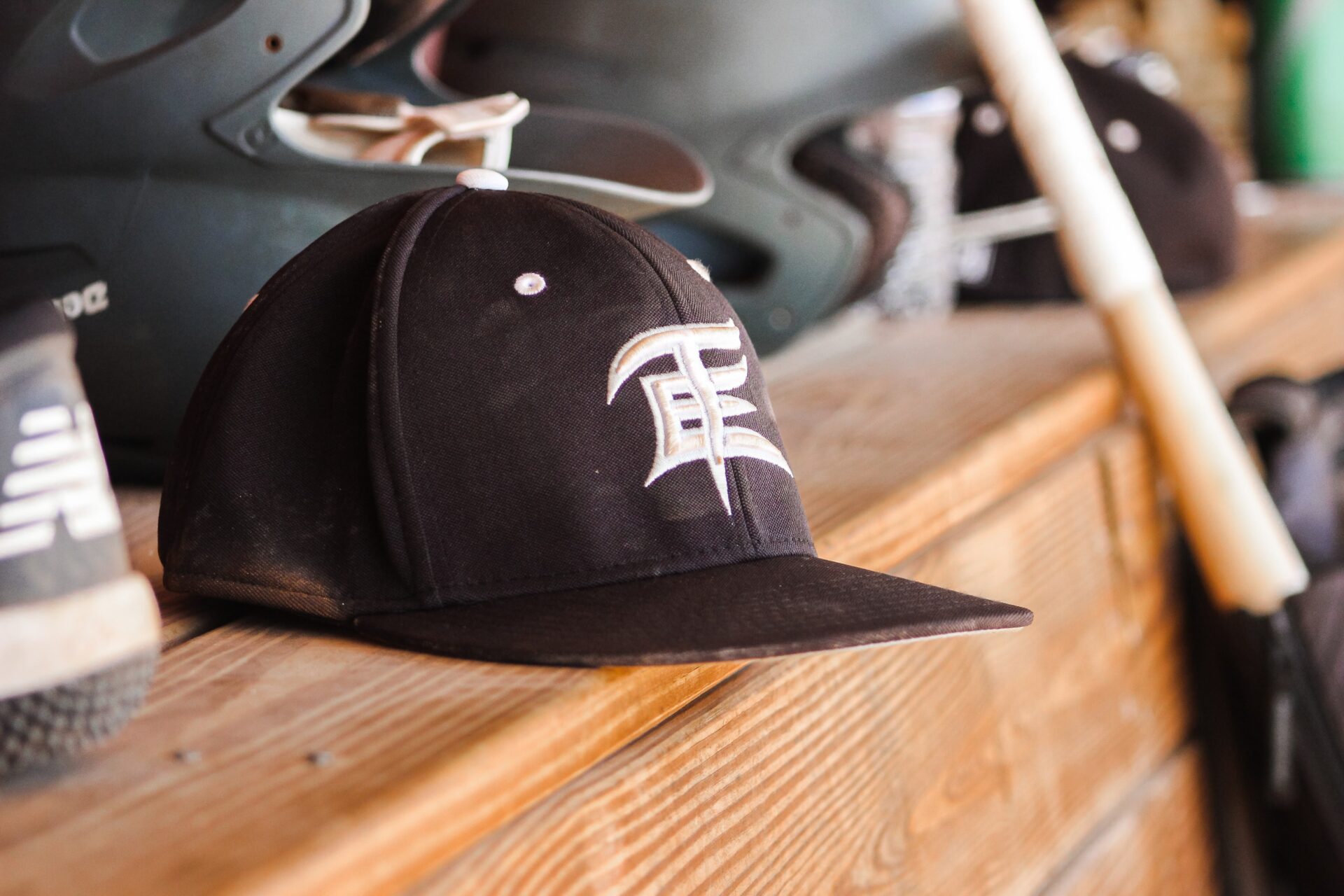 A photograph of a Team Elite baseball hat sitting on a shelf amongst other gear, including shoes and a bat.